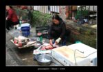 une poissonnière découpe du poisson dans la rue à Hanoï.
